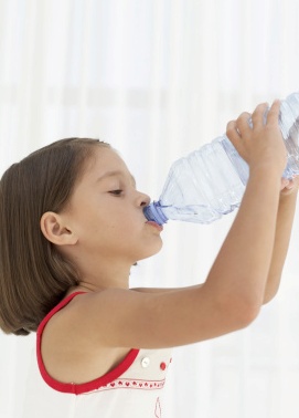 girl (6-7) drinking water from a plastic bottle