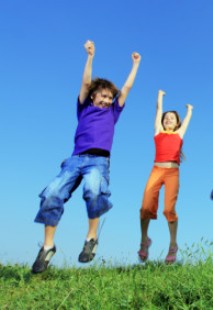 Group of five happy children jumping on meadow.