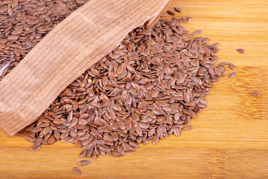 Flax seeds in a transparent package on a wooden background