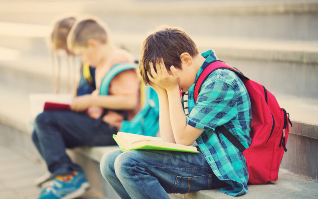 Children with rucksacks sitting on the stairs near school